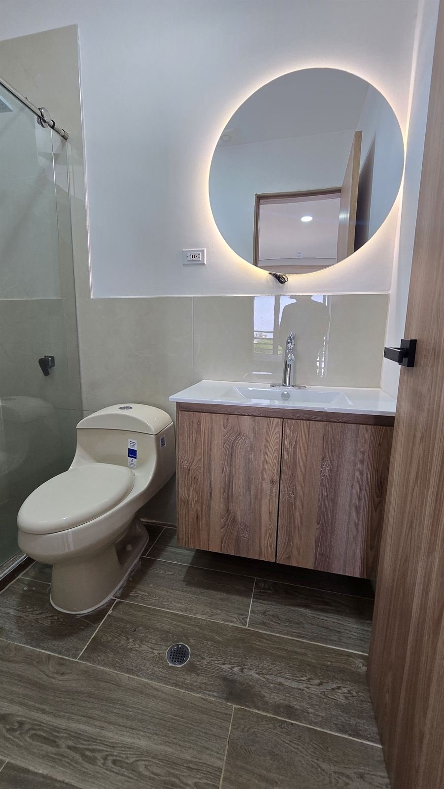 Baño moderno con ducha y espejo redondo iluminado